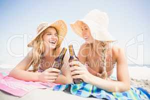 Happy women lying on the beach with beer bottle