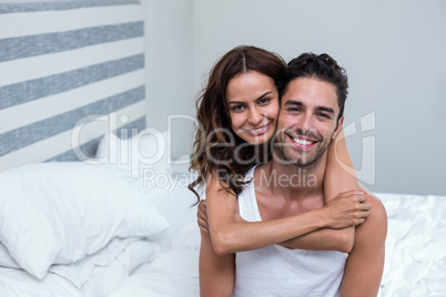 Wife embracing husband on bed at home