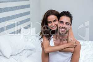 Wife embracing husband on bed at home