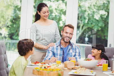 Smiling family with mother standing at dining table