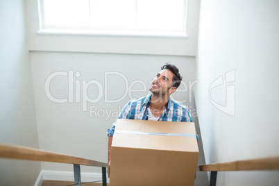 Smiling man holding cardboard box while climbing steps