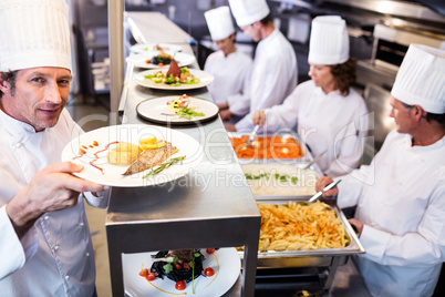Chef handing dinner plates through order station