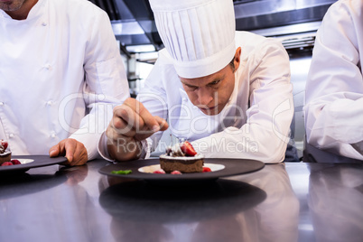 Male chef garnishing dessert plate on counter