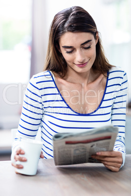 Happy young woman reading newspaper