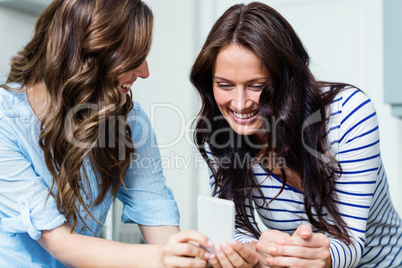 Smiling female friends using mobile phone