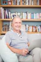 Portrait of happy senior man using laptop