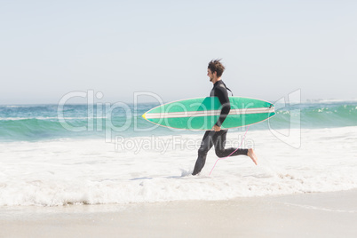 Man with surfboard running towards sea