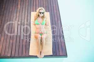 Beautiful woman in green bikini relaxing by poolside