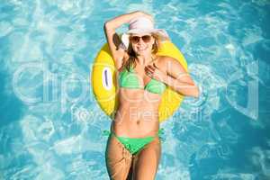 Happy woman in green bikini floating on inflatable tube in swimm