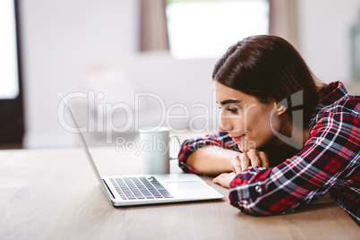 Smiling young woman looking at laptop