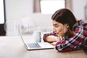 Smiling young woman looking at laptop