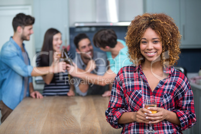 Smiling woman holding wine while friends in background