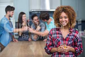 Smiling woman holding wine while friends in background