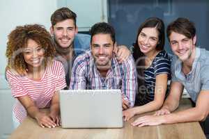 Happy multi-ethnic friends using laptop on table at home