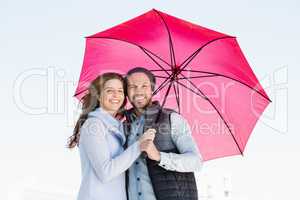 Happy young couple holding pink umbrella