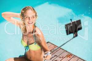 Beautiful woman in bikini taking a selfie by pool side