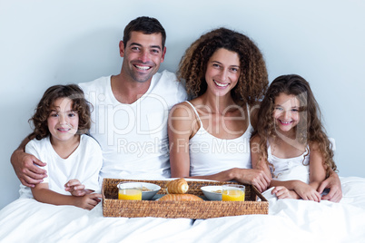 Portrait of a family sitting with breakfast tray in bed