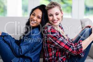 Happy beautiful female friends sitting back to back