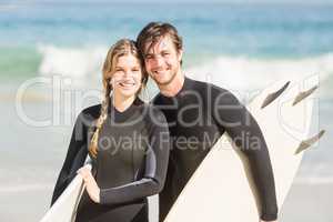 Portrait of couple with surfboard standing on the beach