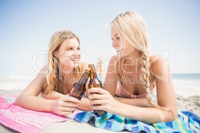 Happy women lying on the beach with beer bottle