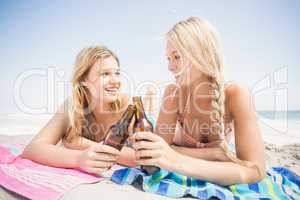 Happy women lying on the beach with beer bottle