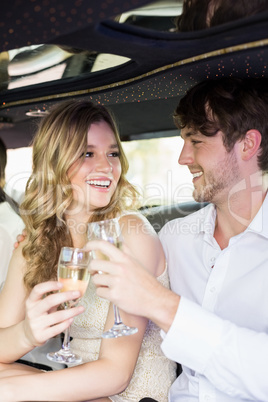 Well dressed couple drinking champagne in a limousine