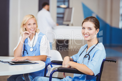 Portrait of smiling female doctor sitting on wheelchair with col