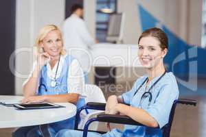 Portrait of smiling female doctor sitting on wheelchair with col