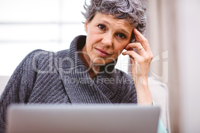 Thoughtful woman using laptop at home