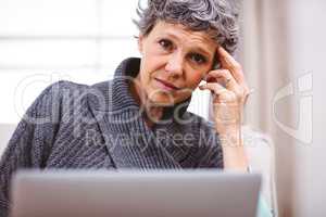 Thoughtful woman using laptop at home