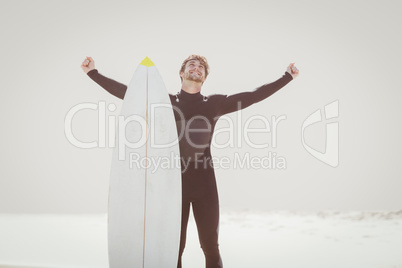 Happy man with surfboard standing on the beach