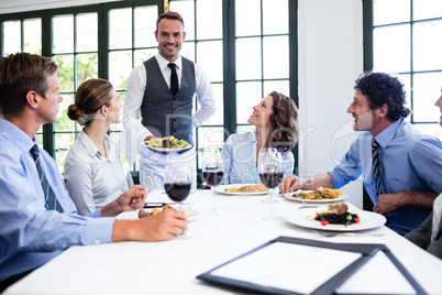 Waiter serving salad to business people