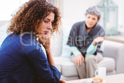 Sad mother and daughter sitting on sofa