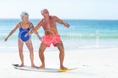 Cute mature couple standing on a surfboard