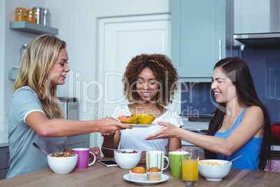 Multi ethnic friends holding plate with papaya in house