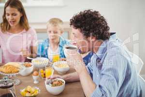 Man drinking tea during breakfast with family
