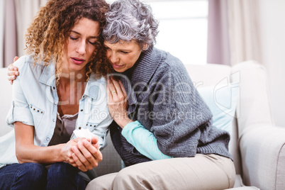 Mother comforting tensed daughter sitting on sofa