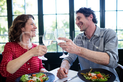 Happy middle-aged couple toasting champagne flutes while having