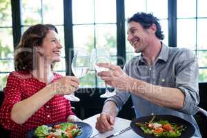 Happy middle-aged couple toasting champagne flutes while having