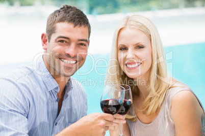 Portrait of smiling couple toasting red wine while sitting by sw