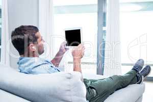 Young man listening to music while using tablet