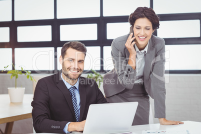 Business people with mobile phone and laptop in office