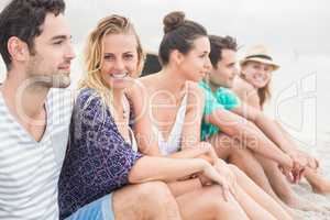 Group of friends sitting side by side on the beach
