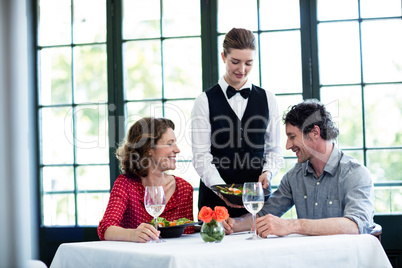 Waitress serving meal to a couple