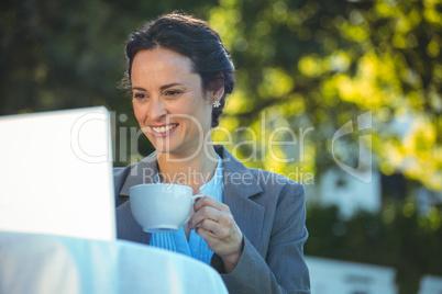 Businesswoman using laptop with coffee