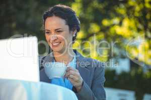 Businesswoman using laptop with coffee