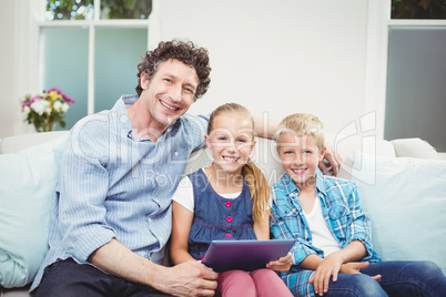 Happy father sitting with children on sofa