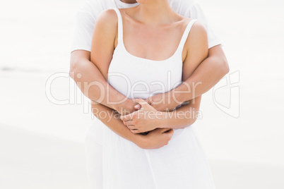 Mid-section of couple embracing on the beach