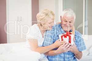 Senior woman giving gift to husband
