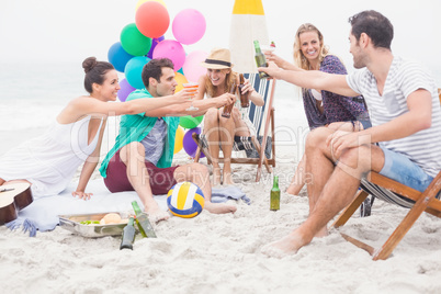 Group of friends toasting beer bottles on the beach